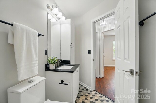 bathroom with toilet, baseboards, and vanity