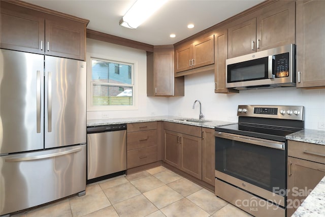 kitchen featuring appliances with stainless steel finishes, light stone countertops, a sink, recessed lighting, and light tile patterned flooring