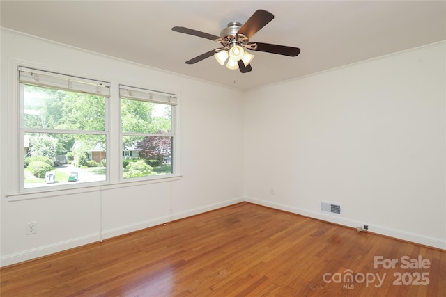 unfurnished room with crown molding, a ceiling fan, baseboards, light wood-type flooring, and visible vents