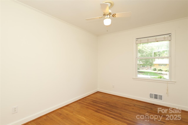 spare room featuring visible vents, crown molding, baseboards, a ceiling fan, and light wood-style flooring