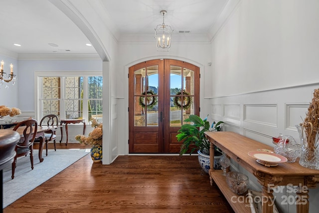 entryway with a chandelier, arched walkways, and a decorative wall