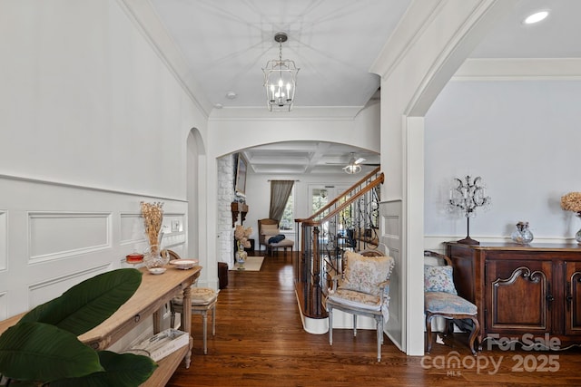 entryway featuring wood finished floors, arched walkways, coffered ceiling, ornamental molding, and stairway
