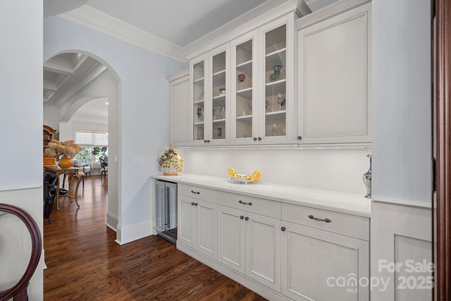 bar with baseboards, ornamental molding, dark wood finished floors, and arched walkways
