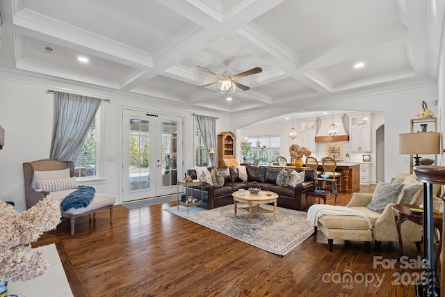 living area with ceiling fan, wood finished floors, coffered ceiling, arched walkways, and french doors