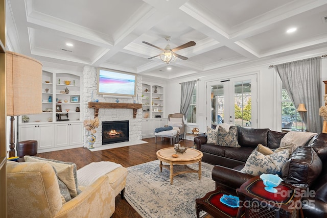 living room featuring beamed ceiling, dark wood-style flooring, a fireplace, french doors, and a ceiling fan