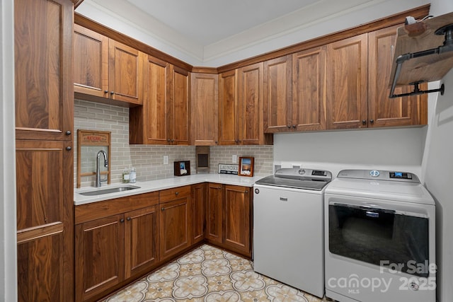 clothes washing area with washing machine and clothes dryer, cabinet space, and a sink
