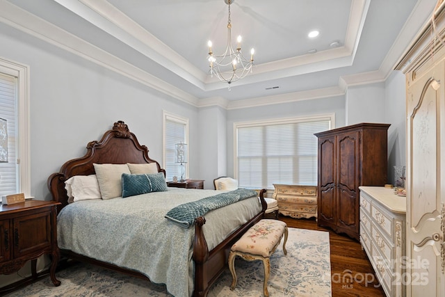 bedroom featuring crown molding, a tray ceiling, dark wood-style flooring, recessed lighting, and a notable chandelier