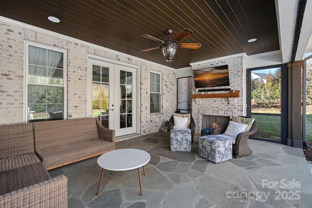 view of patio featuring ceiling fan, french doors, and an outdoor living space with a fireplace