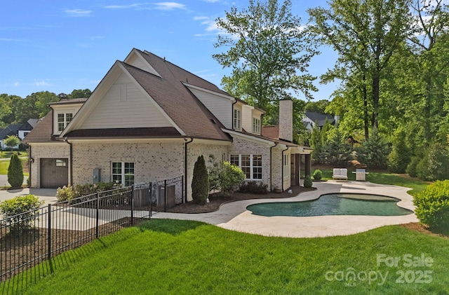 back of property featuring a fenced in pool, a chimney, fence, a yard, and brick siding