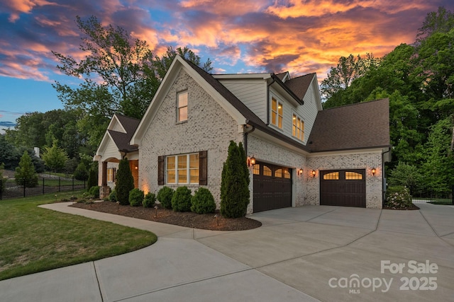 view of front of house with brick siding, fence, driveway, a front yard, and an attached garage