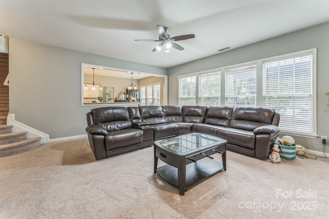 carpeted living area featuring ceiling fan, stairs, baseboards, and visible vents