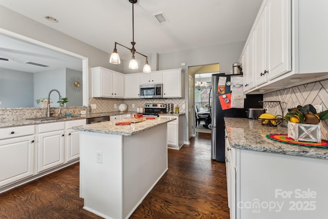 kitchen featuring visible vents, a sink, backsplash, stainless steel appliances, and white cabinets