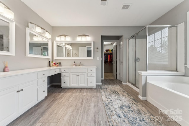 full bath with a stall shower, visible vents, a garden tub, vanity, and wood finished floors