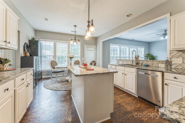 kitchen with a sink, ceiling fan with notable chandelier, dishwasher, dark wood-style floors, and light stone countertops