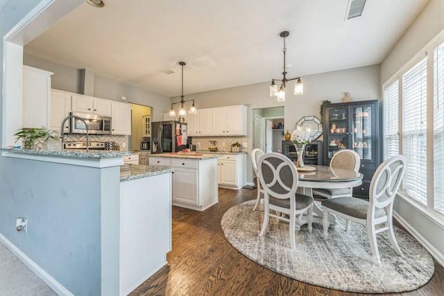 kitchen featuring an inviting chandelier, refrigerator with ice dispenser, visible vents, stainless steel microwave, and plenty of natural light