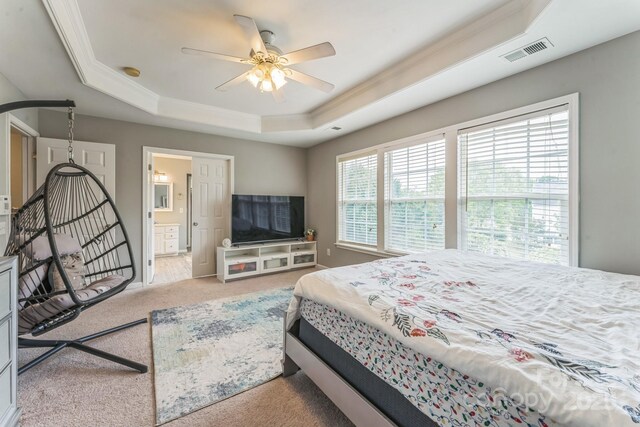 bedroom with visible vents, crown molding, carpet floors, a raised ceiling, and connected bathroom