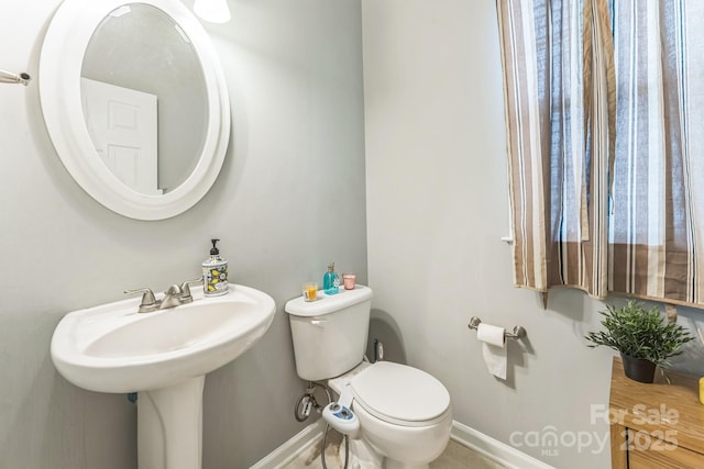 bathroom with a sink, toilet, and baseboards