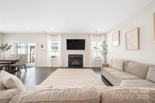 living room featuring a healthy amount of sunlight, recessed lighting, dark wood finished floors, and a fireplace with flush hearth