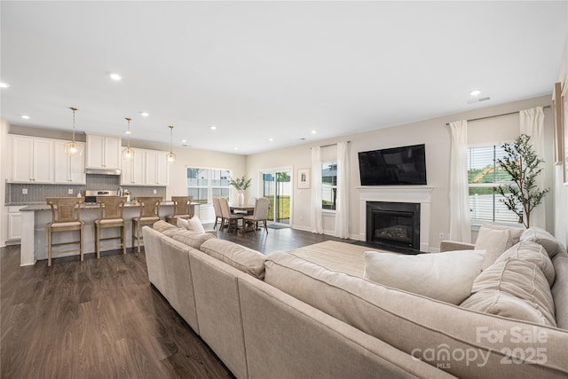 living room featuring recessed lighting, dark wood-style floors, and a wealth of natural light