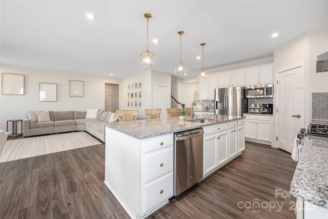 kitchen featuring decorative backsplash, an island with sink, white cabinets, a sink, and appliances with stainless steel finishes