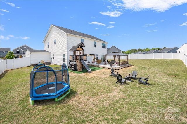 rear view of house with a lawn, a playground, a gazebo, a trampoline, and an outdoor fire pit