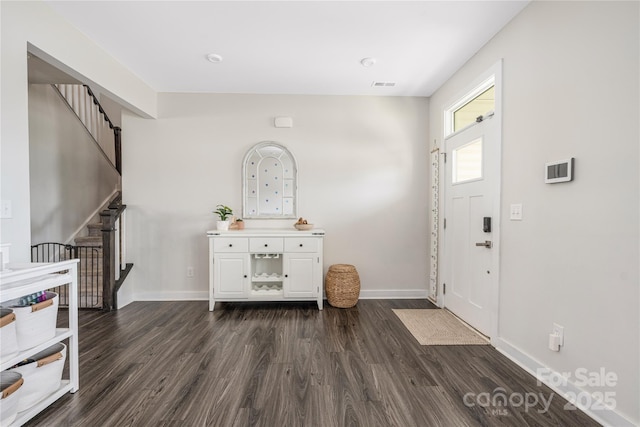 foyer featuring baseboards, visible vents, stairs, and dark wood-type flooring