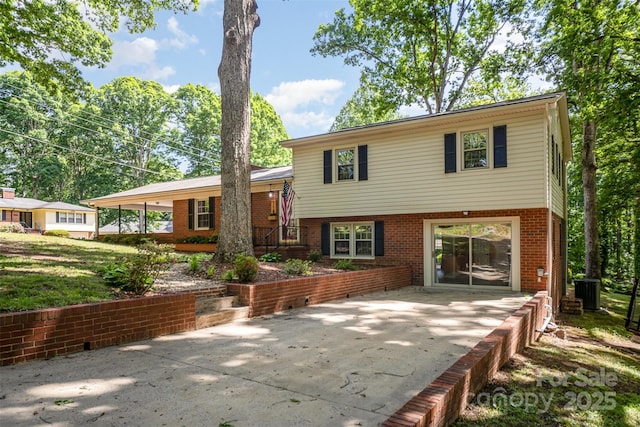 rear view of property with brick siding, a patio, and driveway