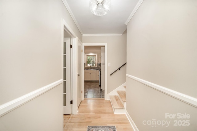 hallway featuring crown molding, light wood-type flooring, and stairway