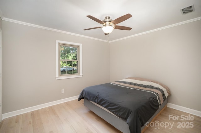 bedroom featuring wood finished floors, baseboards, ornamental molding, and a ceiling fan