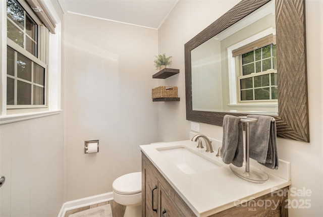 half bathroom with toilet, vanity, and baseboards