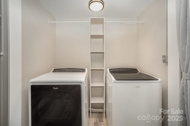 clothes washing area with washer and dryer and wood finished floors