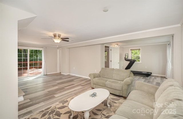 living room with light wood-style flooring, crown molding, baseboards, ceiling fan, and plenty of natural light