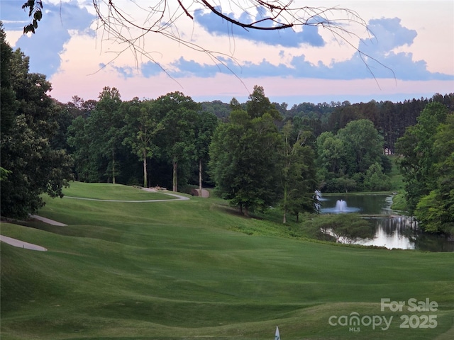 view of home's community with a water view, a lawn, golf course view, and a forest view