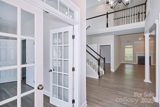 interior space with a towering ceiling, wood finished floors, baseboards, a fireplace, and a chandelier