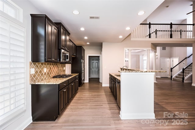 kitchen with stainless steel appliances, light stone counters, recessed lighting, tasteful backsplash, and light wood finished floors