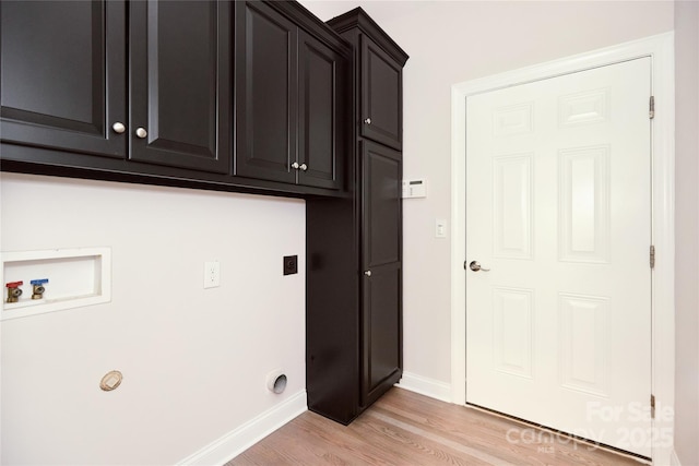 washroom featuring cabinet space, hookup for an electric dryer, light wood-style floors, washer hookup, and baseboards