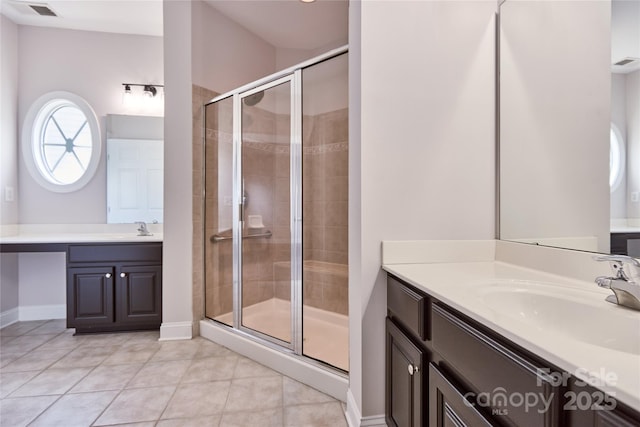 bathroom with a stall shower, tile patterned flooring, baseboards, and two vanities