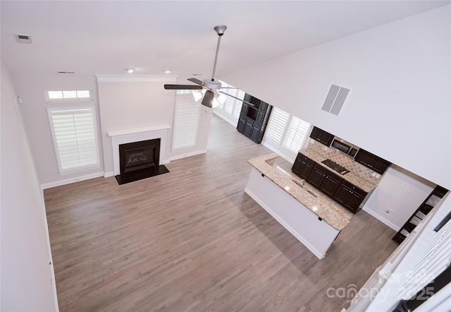 unfurnished living room with light wood-style floors, a ceiling fan, a fireplace with flush hearth, and baseboards