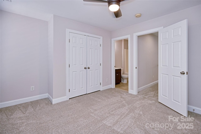 unfurnished bedroom featuring light colored carpet, baseboards, a closet, ceiling fan, and connected bathroom