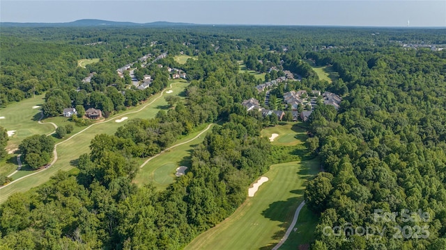 aerial view of property's location featuring a heavily wooded area and a golf club