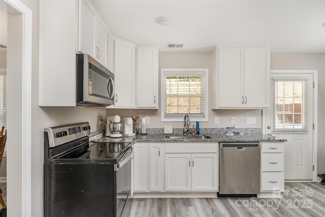 658 Morgan Rd, Albemarle, NC 28001 - kitchen featuring white cabinets, appliances with stainless steel finishes, a sink, light wood finished floors, and stone counters