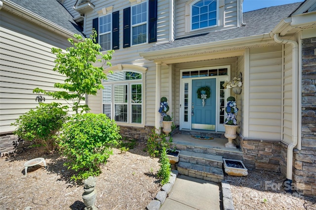 property entrance with a shingled roof and stone siding
