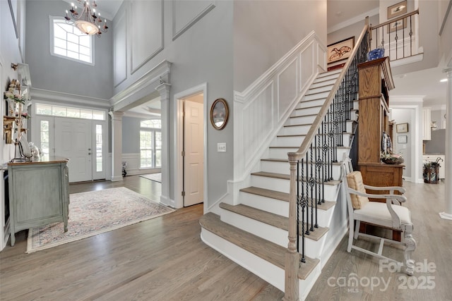 entrance foyer featuring stairway, decorative columns, wood finished floors, and a towering ceiling