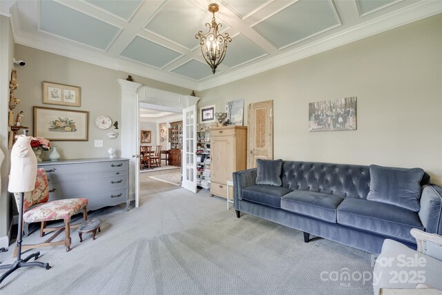 carpeted living room with crown molding, coffered ceiling, ornate columns, and a notable chandelier