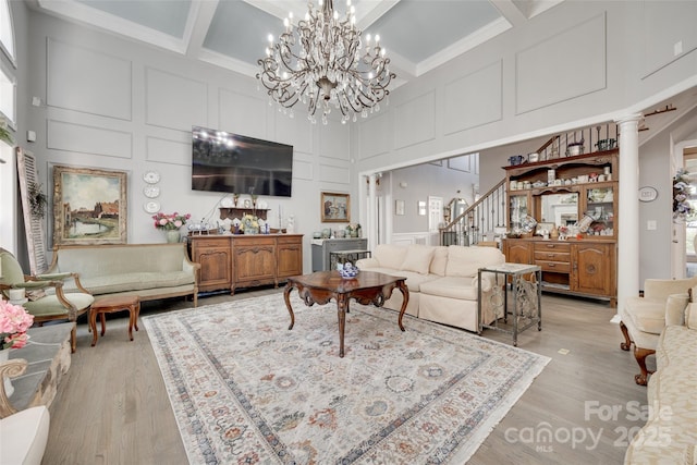 living room featuring light wood-type flooring, a high ceiling, and a decorative wall
