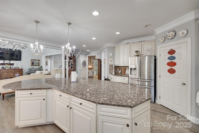 kitchen with ornamental molding, a kitchen island, stainless steel fridge, light wood finished floors, and a notable chandelier