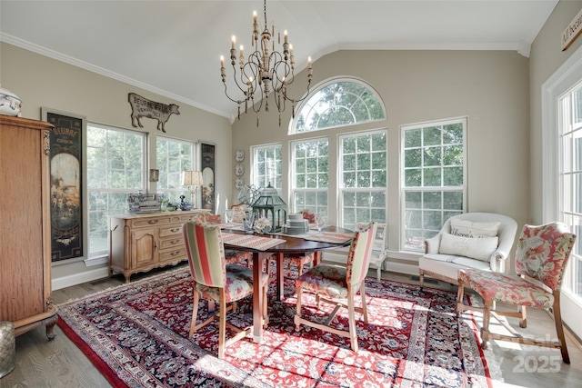 dining space with ornamental molding, lofted ceiling, wood finished floors, and a notable chandelier