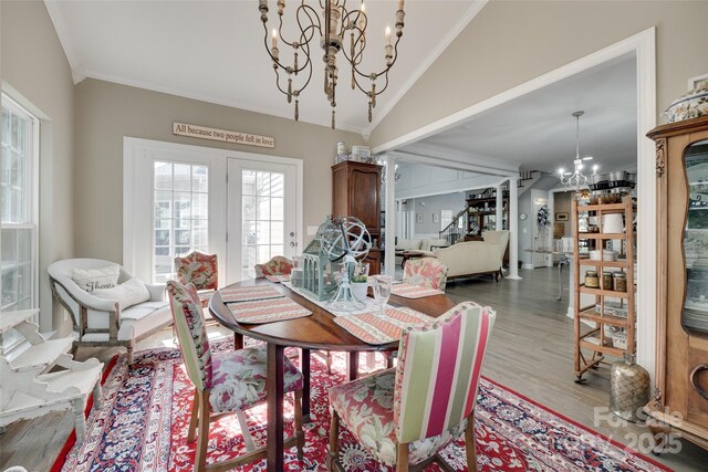dining area with ornamental molding, lofted ceiling, wood finished floors, and a notable chandelier