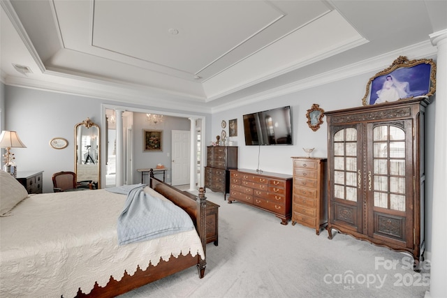 carpeted bedroom with a tray ceiling, ornamental molding, decorative columns, and visible vents