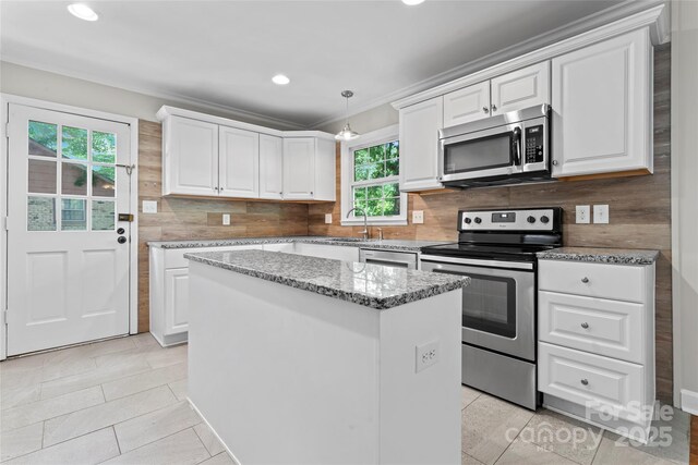 kitchen with white cabinets, a center island, stainless steel appliances, light tile patterned floors, and backsplash